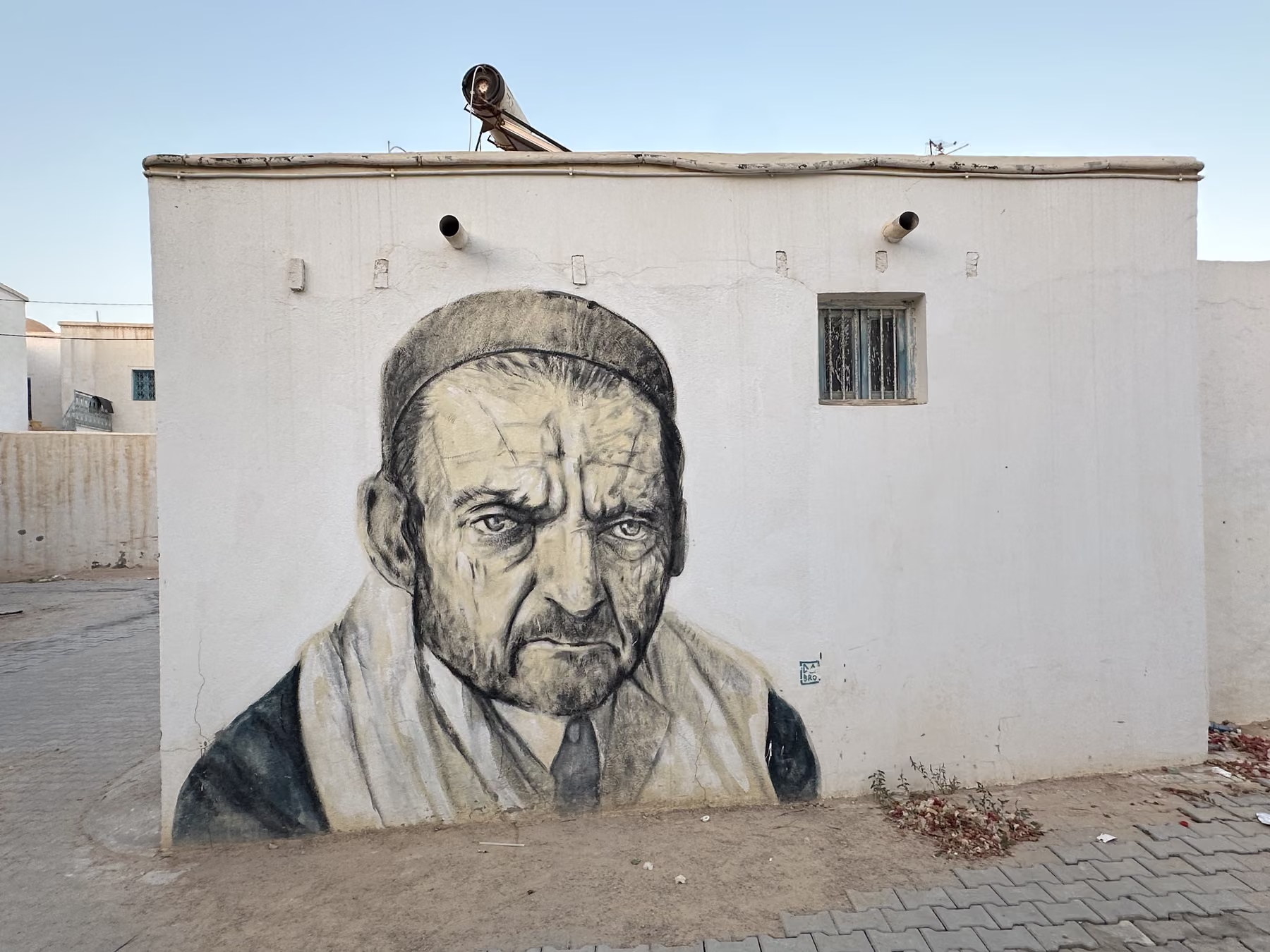 Grande fresque représentant un portrait sur une façade blanche de Djerbahood